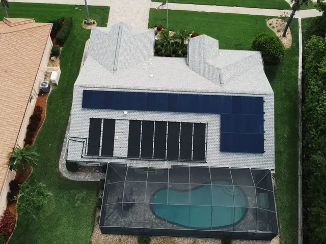 Aerial view of a home with solar panels on the roof and a pool beside it
