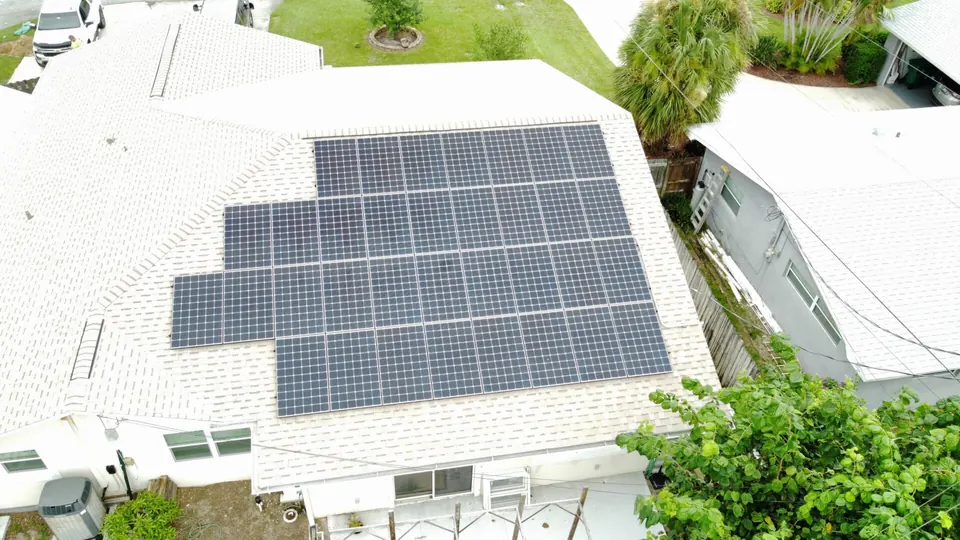 Aerial view of a white-roofed home with a large solar panel array
