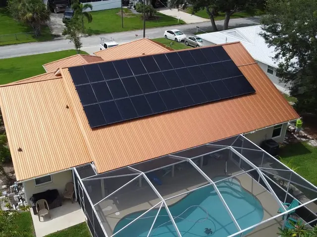 Aerial view of a home with a pool enclosure and rooftop solar panels