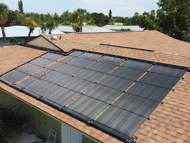Black solar pool heating collectors on a shingle roof