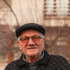 Portrait of a smiling older man in a flat cap and glasses