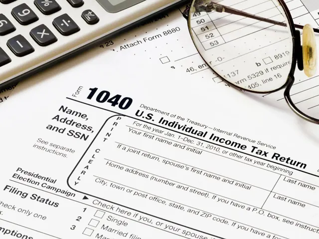 Tax form with a calculator and reading glasses on a desk
