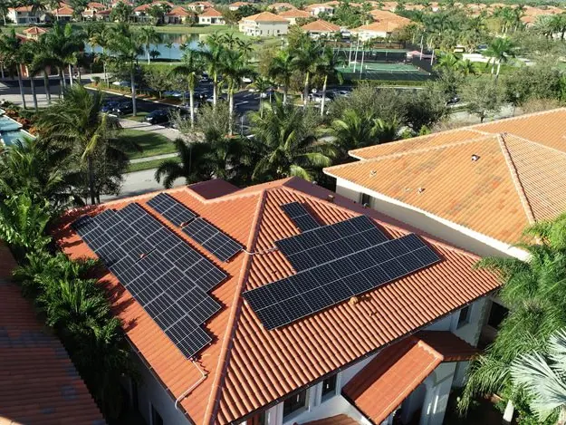 Aerial view of a terracotta tile roof with solar panels and palm trees